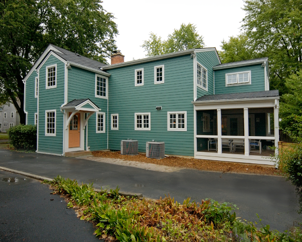 A large green house with a screened in porch