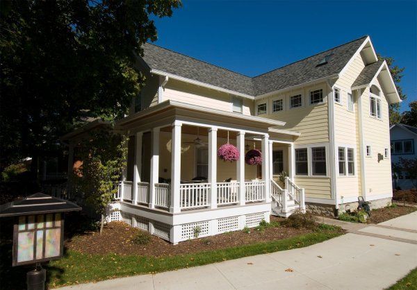 A large white house with a large porch and a gray roof.