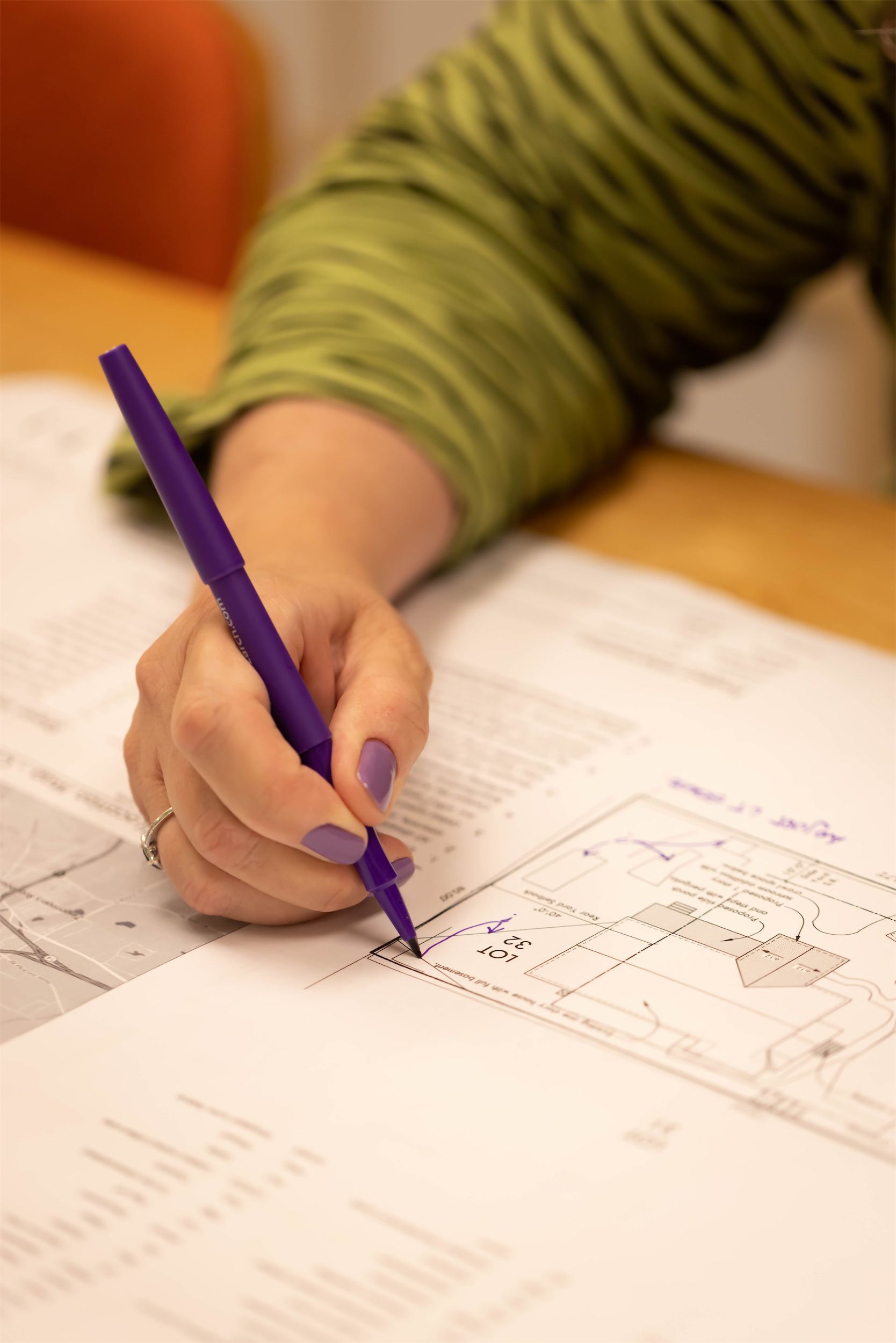 A person is writing on a piece of paper with a purple pen