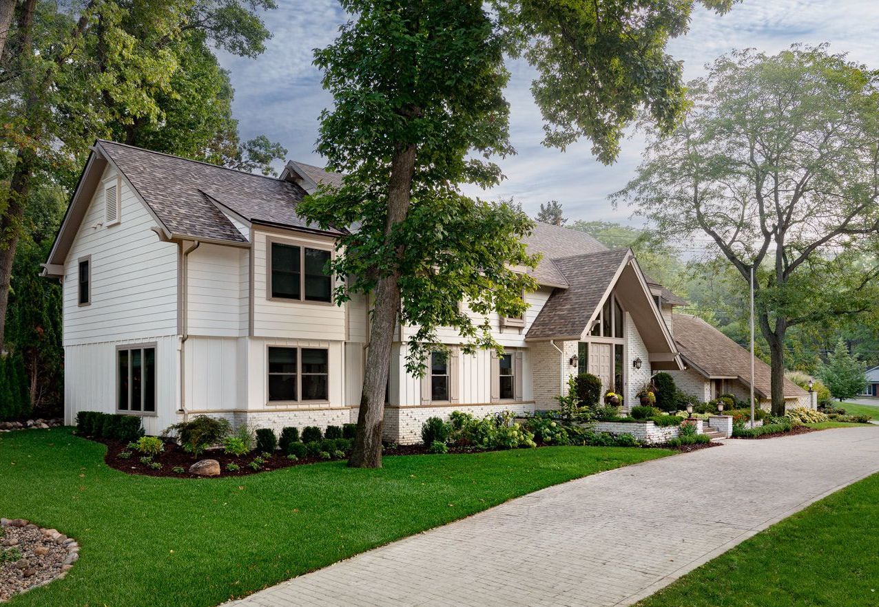 A large white house with a gravel driveway leading to it.