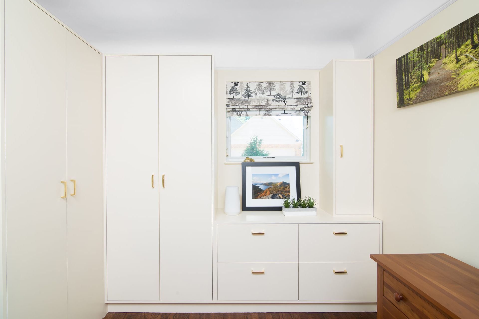 A room with white cabinets and drawers and a picture on the wall.