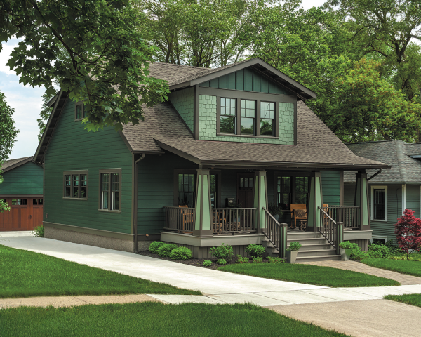 A green house with a brown roof and a porch