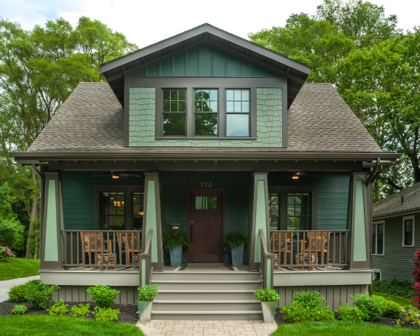A green and brown house with a porch and stairs