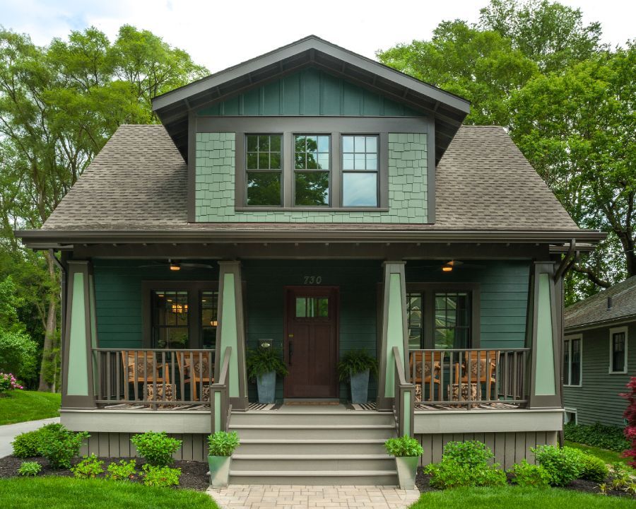 A green and brown house with a porch and stairs
