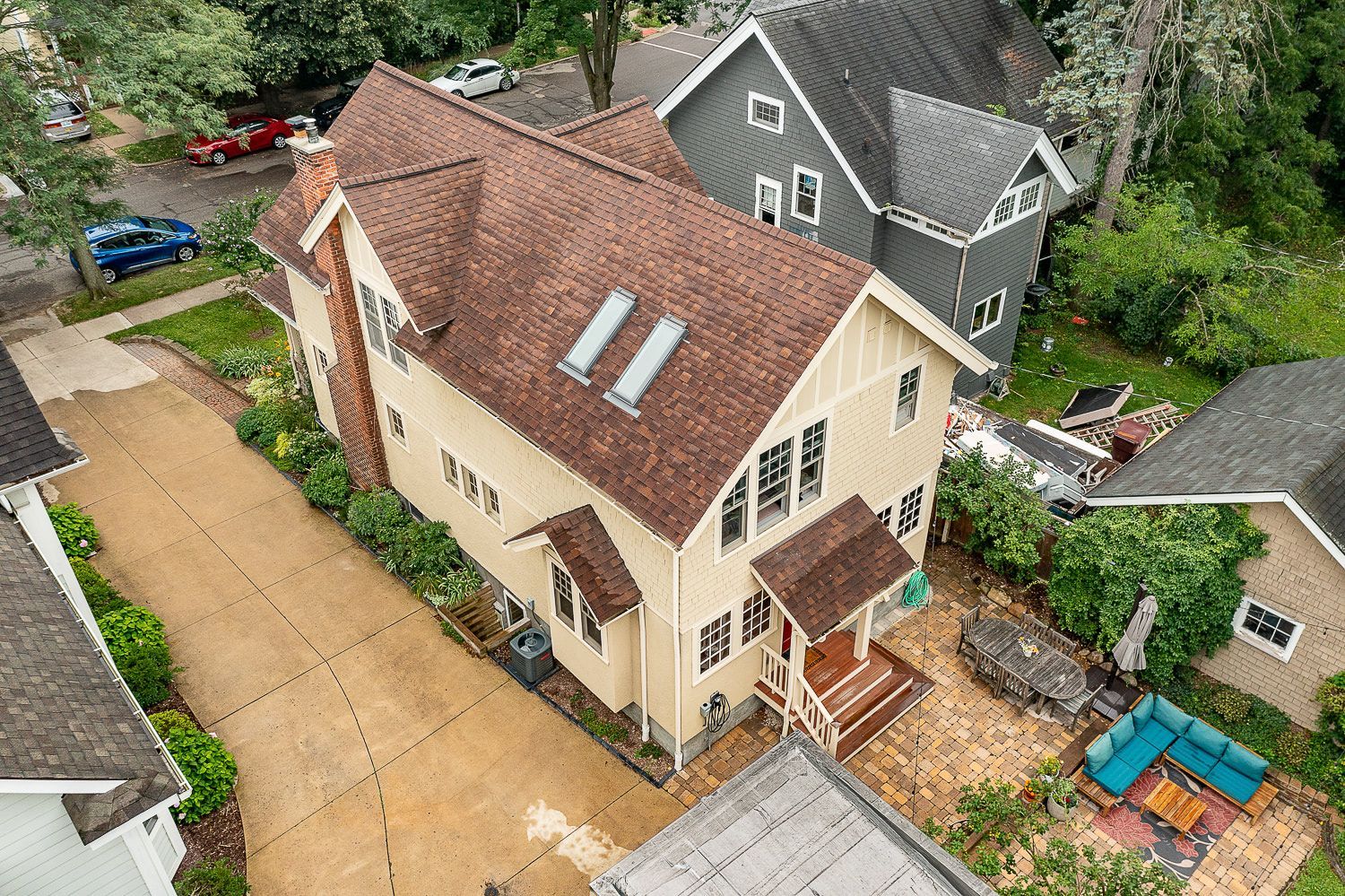 A wooden deck along the back of a house leading to a door and room with a wall of windows.