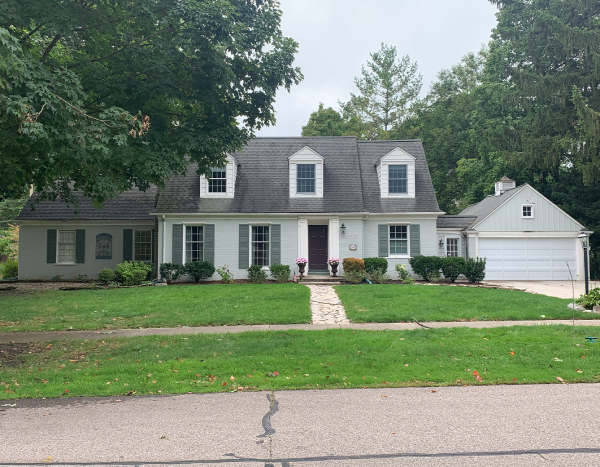 A white house with a black roof and a white garage