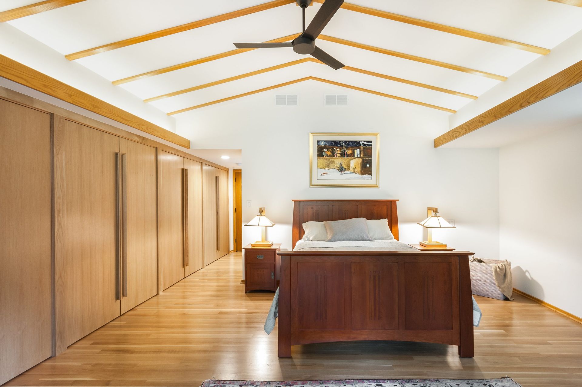 A bedroom with a ceiling fan and a large bed.