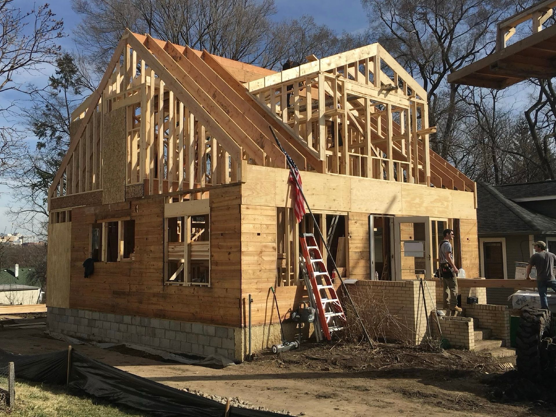 A wooden house is being built with a ladder in front of it.