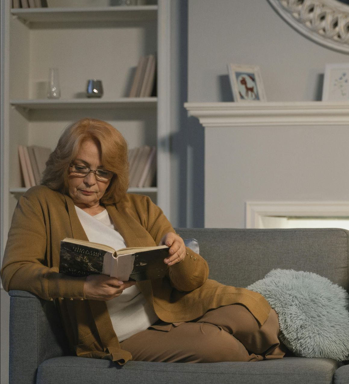 A woman is sitting on a couch reading a book