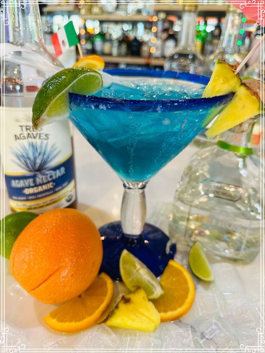 Blue margarita cocktail garnished with fruit and small Mexican flag.