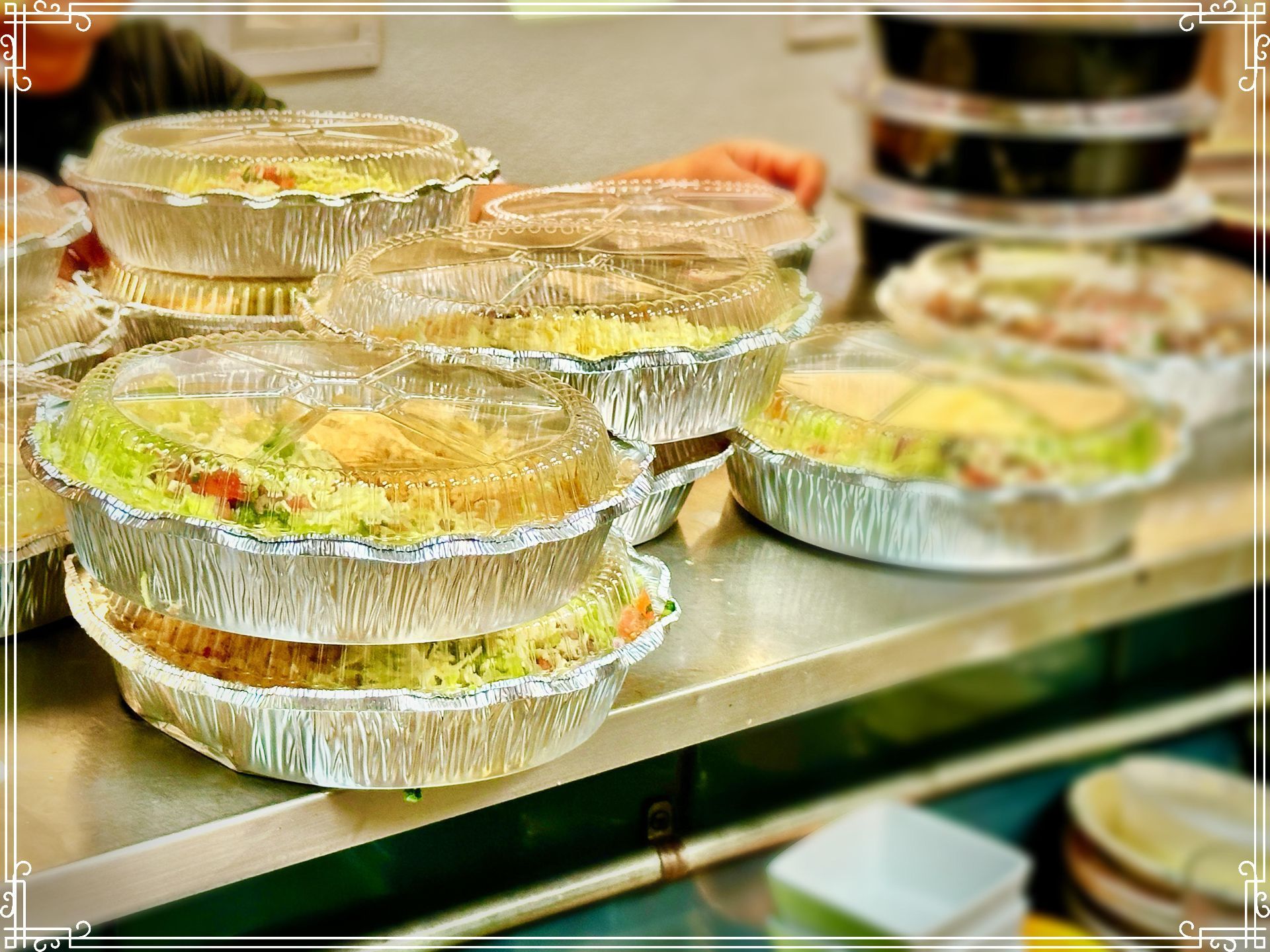 Aluminum foil containers stacked with prepared food, ready for delivery.