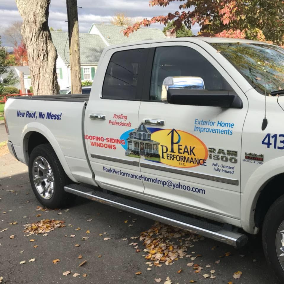 White service pickup truck with Peak Performance branding parked by a tree on a leaf-covered street White service pickup truck with Peak Performance branding parked by a tree on a leaf-covered street