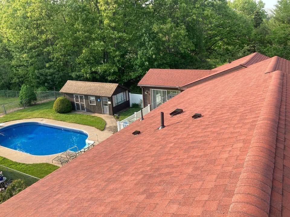 Rooftop view of a red-tiled house beside a backyard pool and small shed, surrounded by trees. Rooftop view of a red-tiled house beside a backyard pool and small shed, surrounded by trees.