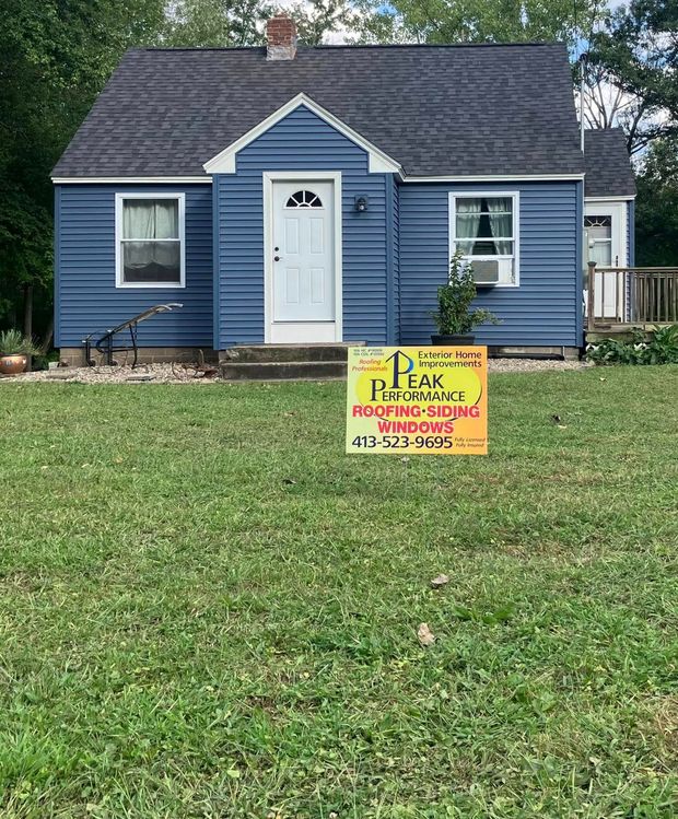 Blue house with a front lawn and a yard sign offering landscaping services Blue house with a front lawn and a yard sign offering landscaping services