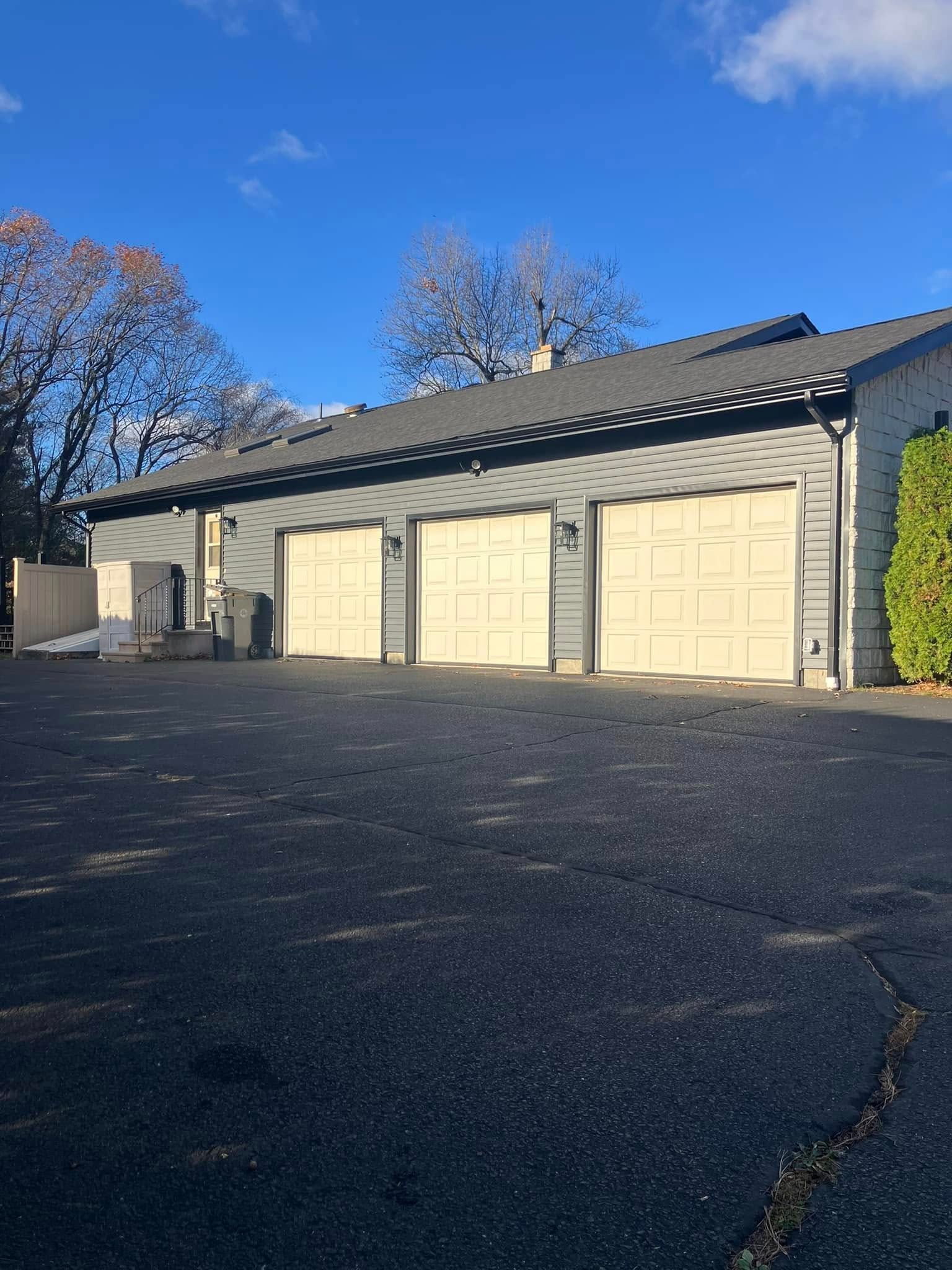 Row of beige garage doors beside a dark asphalt lot under a clear blue sky Row of beige garage doors beside a dark asphalt lot under a clear blue sky