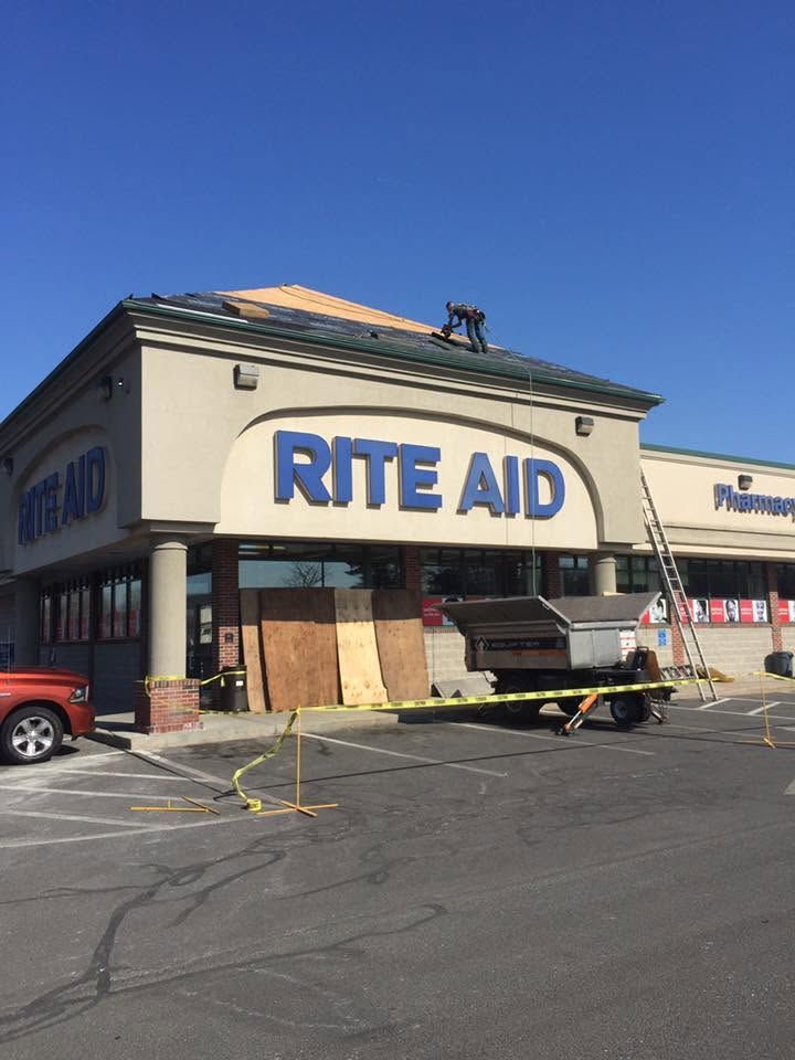 Rite Aid storefront with damaged roof and boarded windows in a parking lot Rite Aid storefront with damaged roof and boarded windows in a parking lot