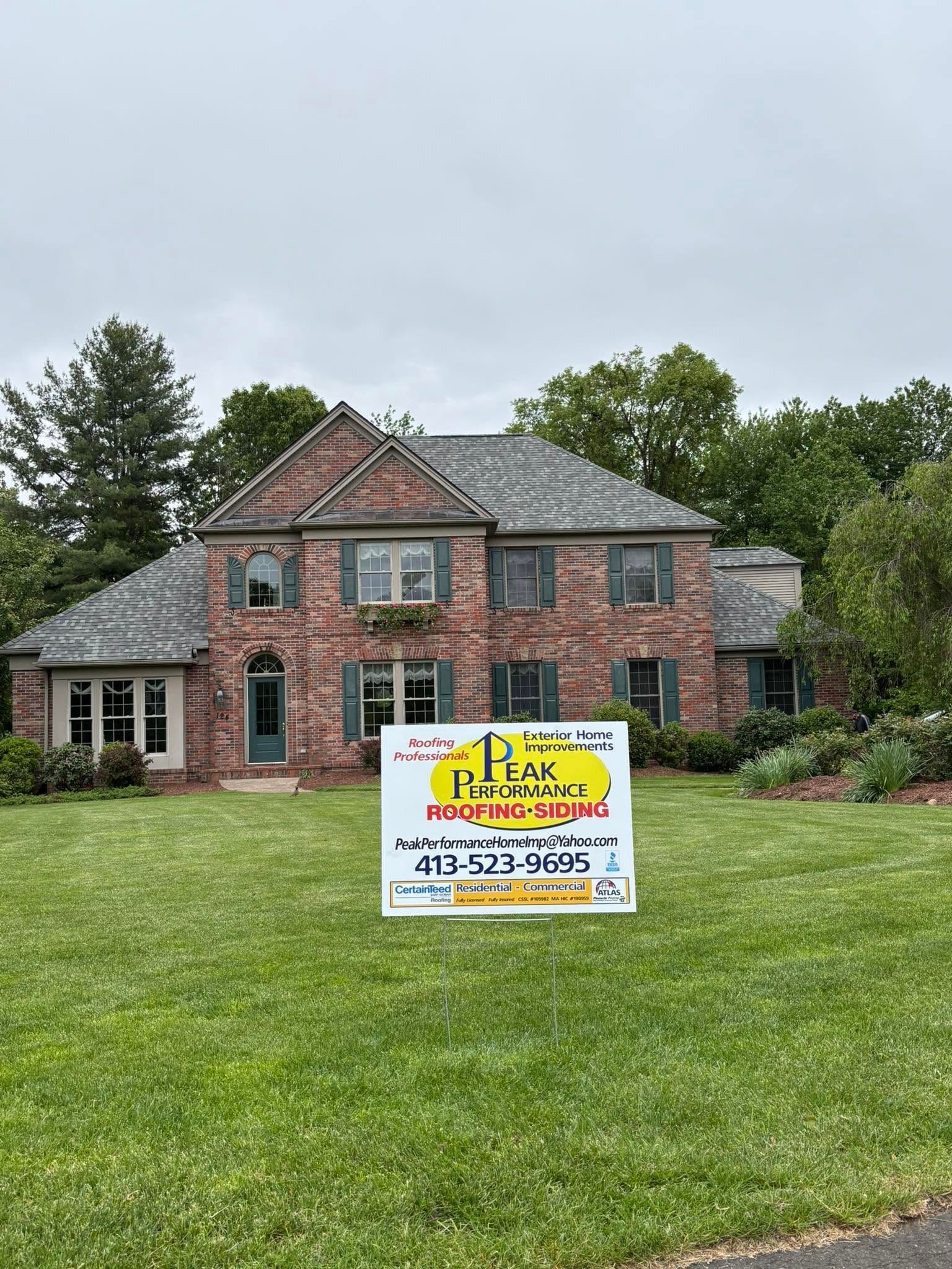 Brick house with a lawn sign advertising a real estate listing under a cloudy sky Brick house with a lawn sign advertising a real estate listing under a cloudy sky