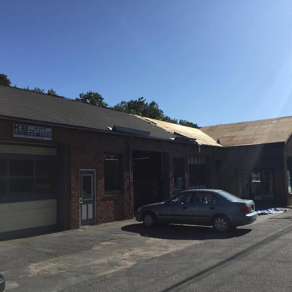 Sunlit brick storefront with a parked gray sedan in front of a garage bay Sunlit brick storefront with a parked gray sedan in front of a garage bay