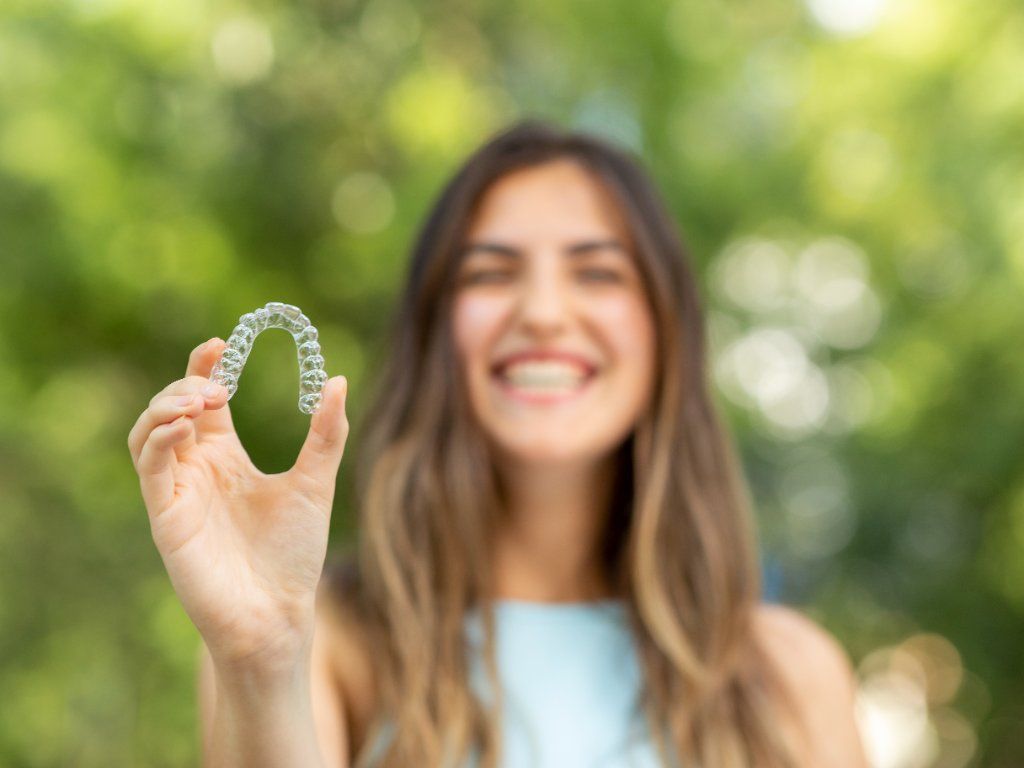 woman holding up invisalign