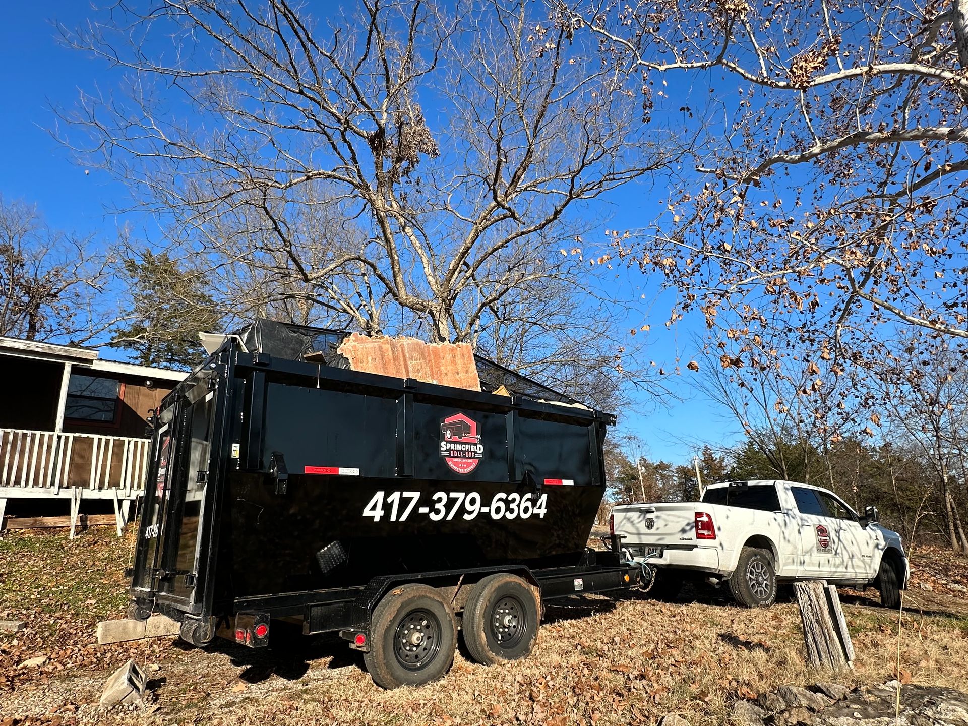A truck and trailer are parked in front of a house.