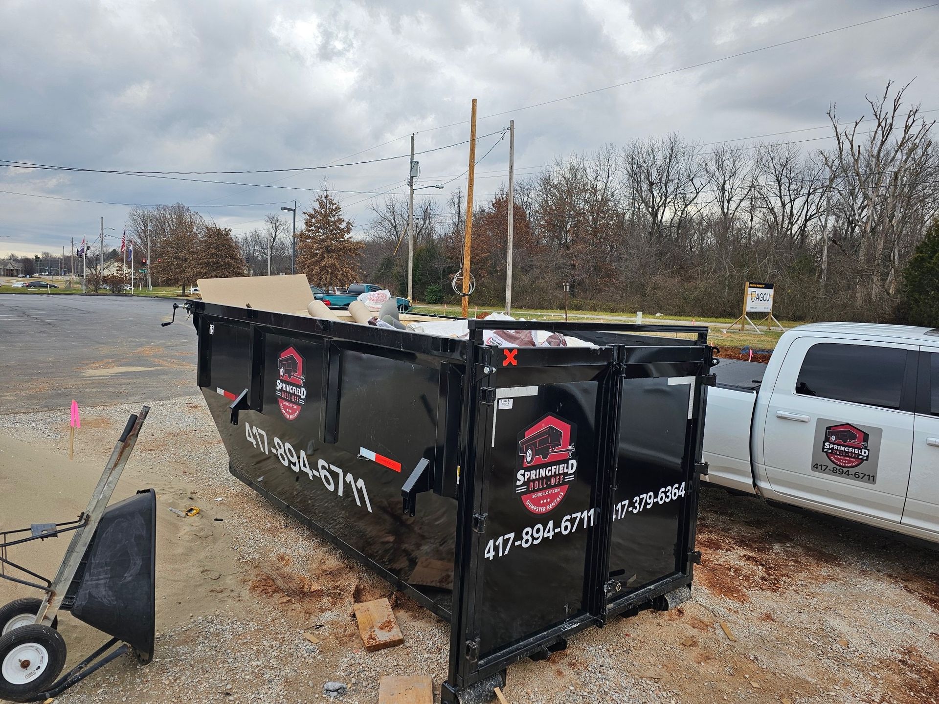 A dumpster is sitting next to a truck in a parking lot.