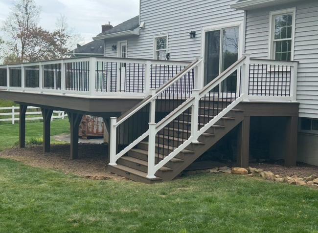 White house deck with stairs and black railings over a grassy yard