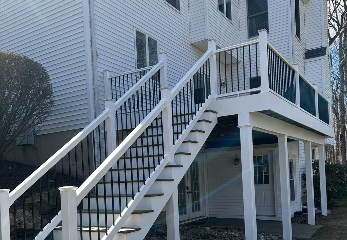 Exterior white staircase and raised deck on a light-colored building with black railings