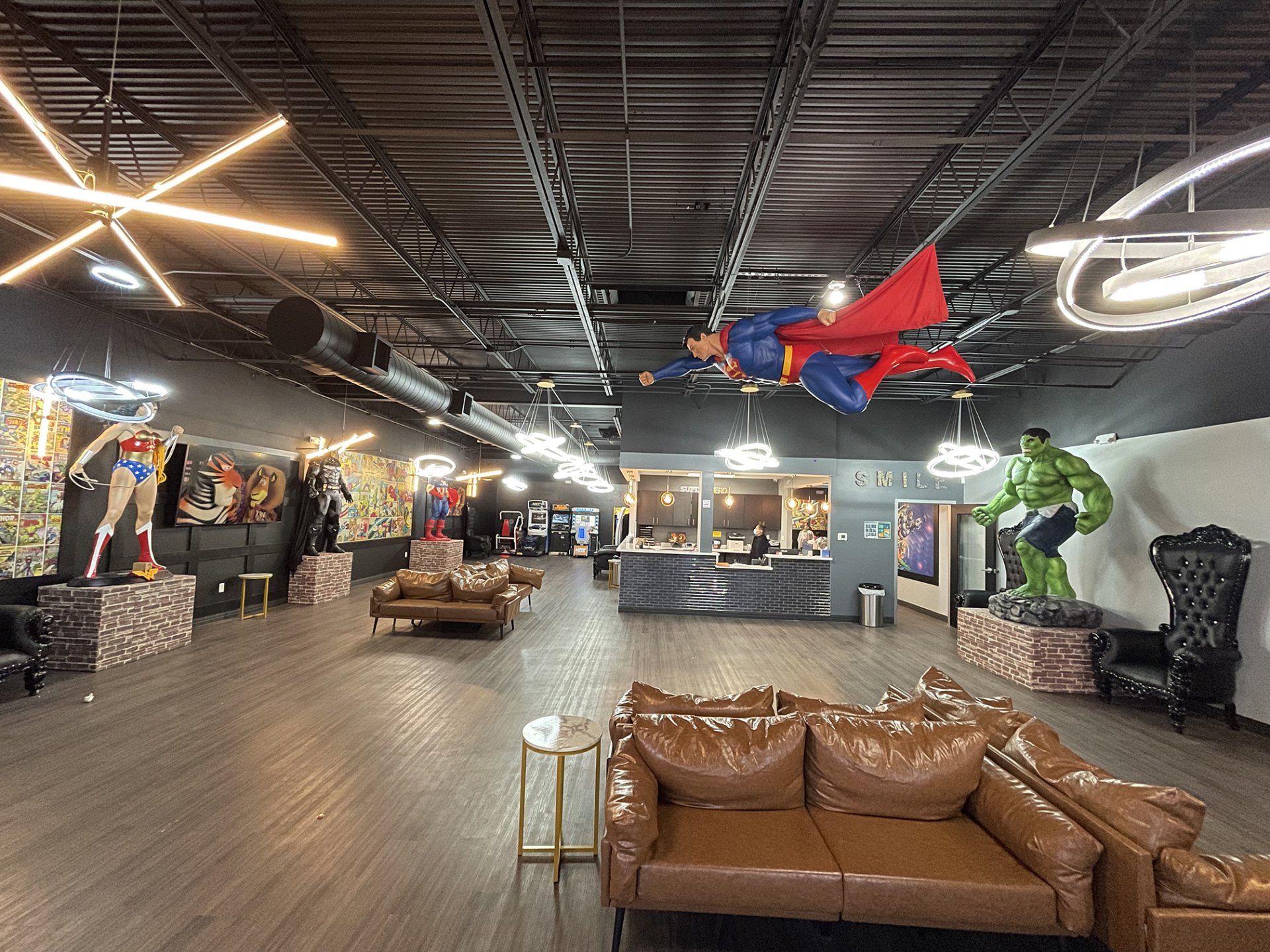 Indoor showroom with superhero statues, leather sofa seating, and neon ceiling lights