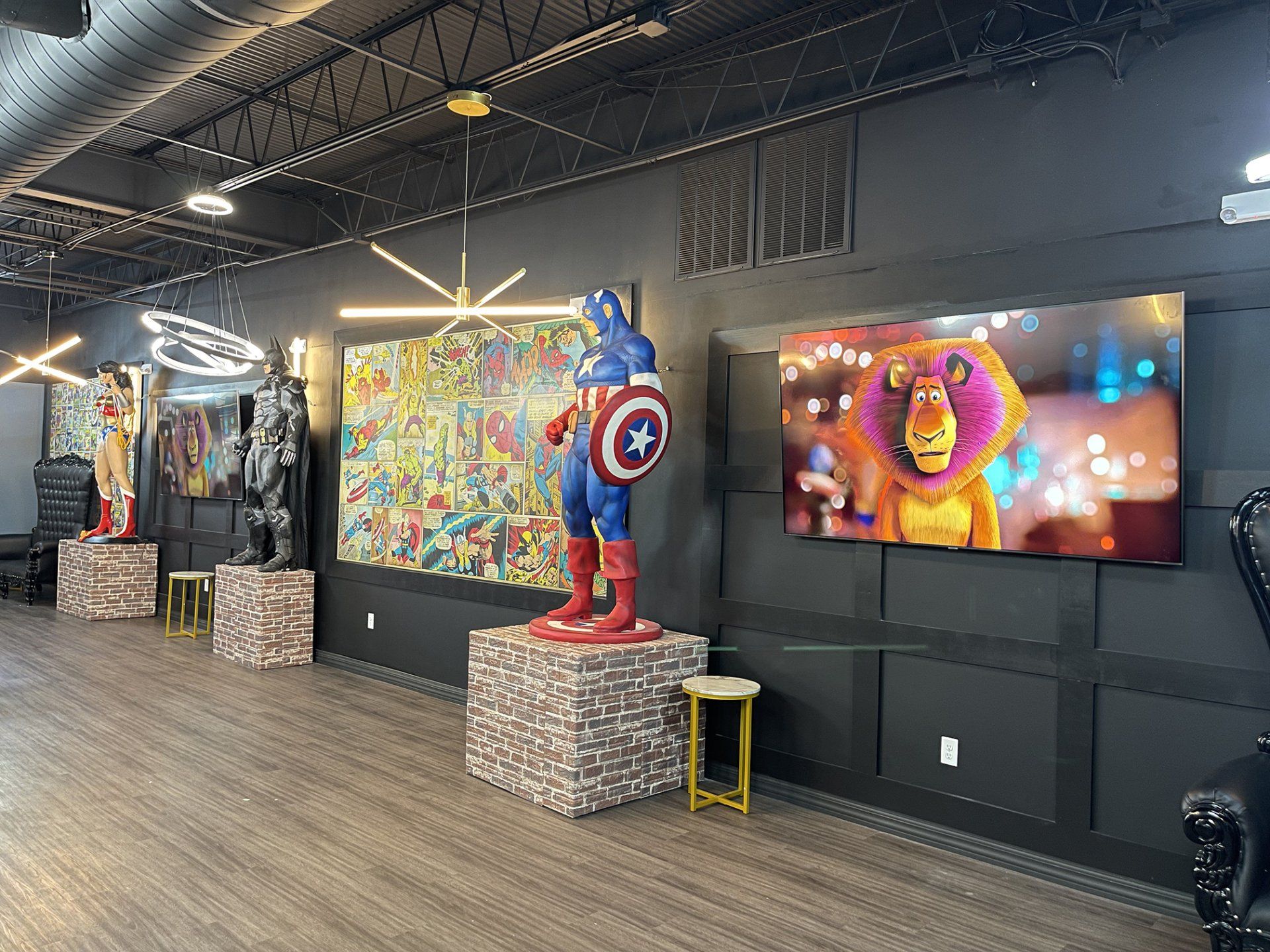 Comic art gallery with superhero statues, colorful wall art, and a glowing TV screen in a dark exhibit room