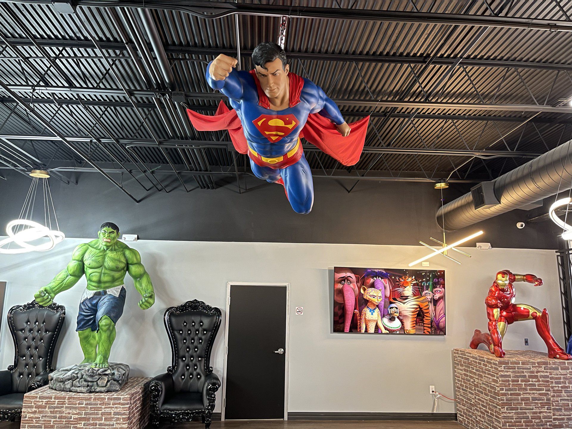 Superman ceiling display in a comic shop with Hulk and Iron Man statues below