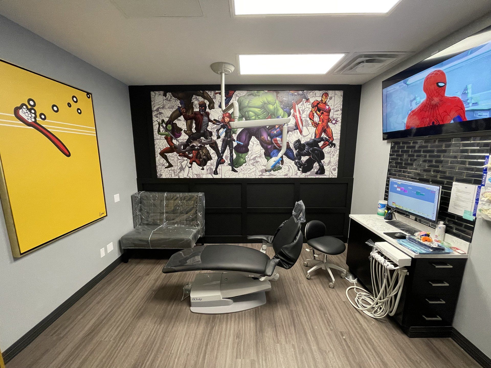 Modern office lounge with gray chairs, couch, anime wall art, and a Spider-Man TV on the wall