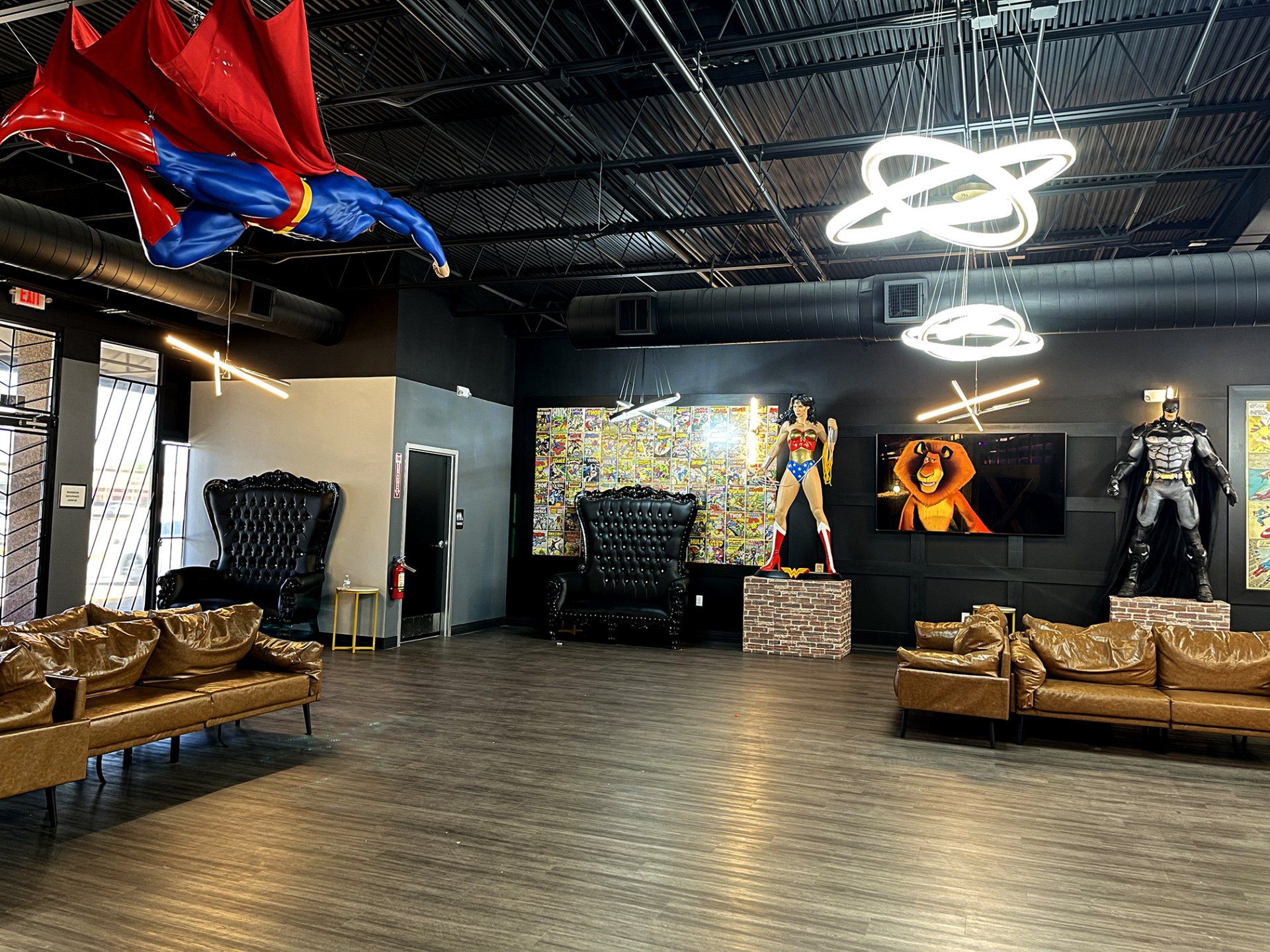 Modern industrial lounge with tan couches, neon ring lights, and comic-style wall art in a spacious room