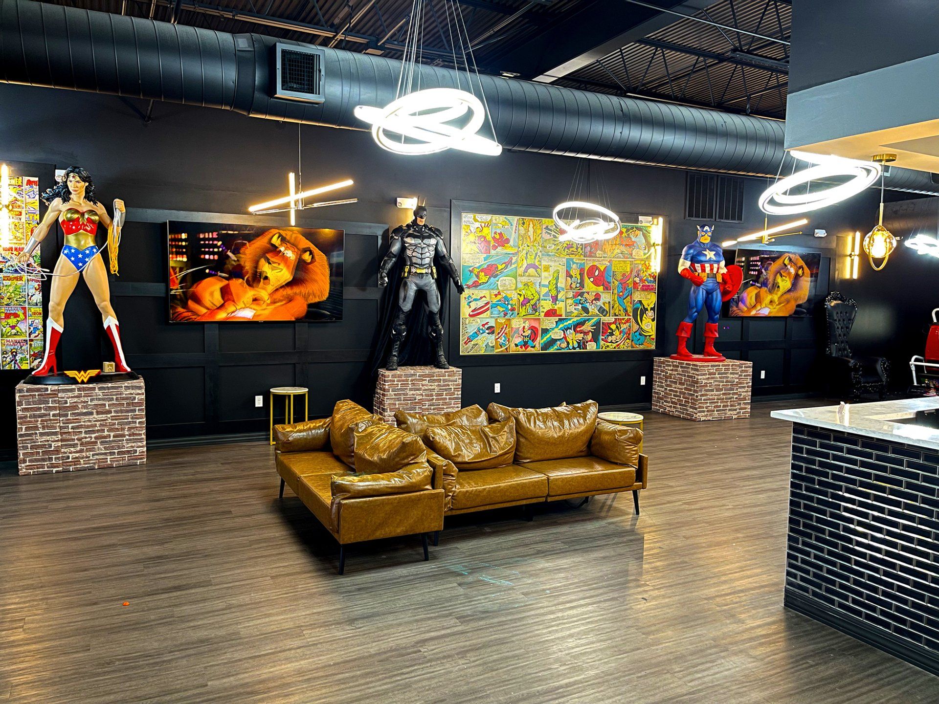 Superhero-themed lounge with statues, colorful art, leather sofa, and neon ring lights