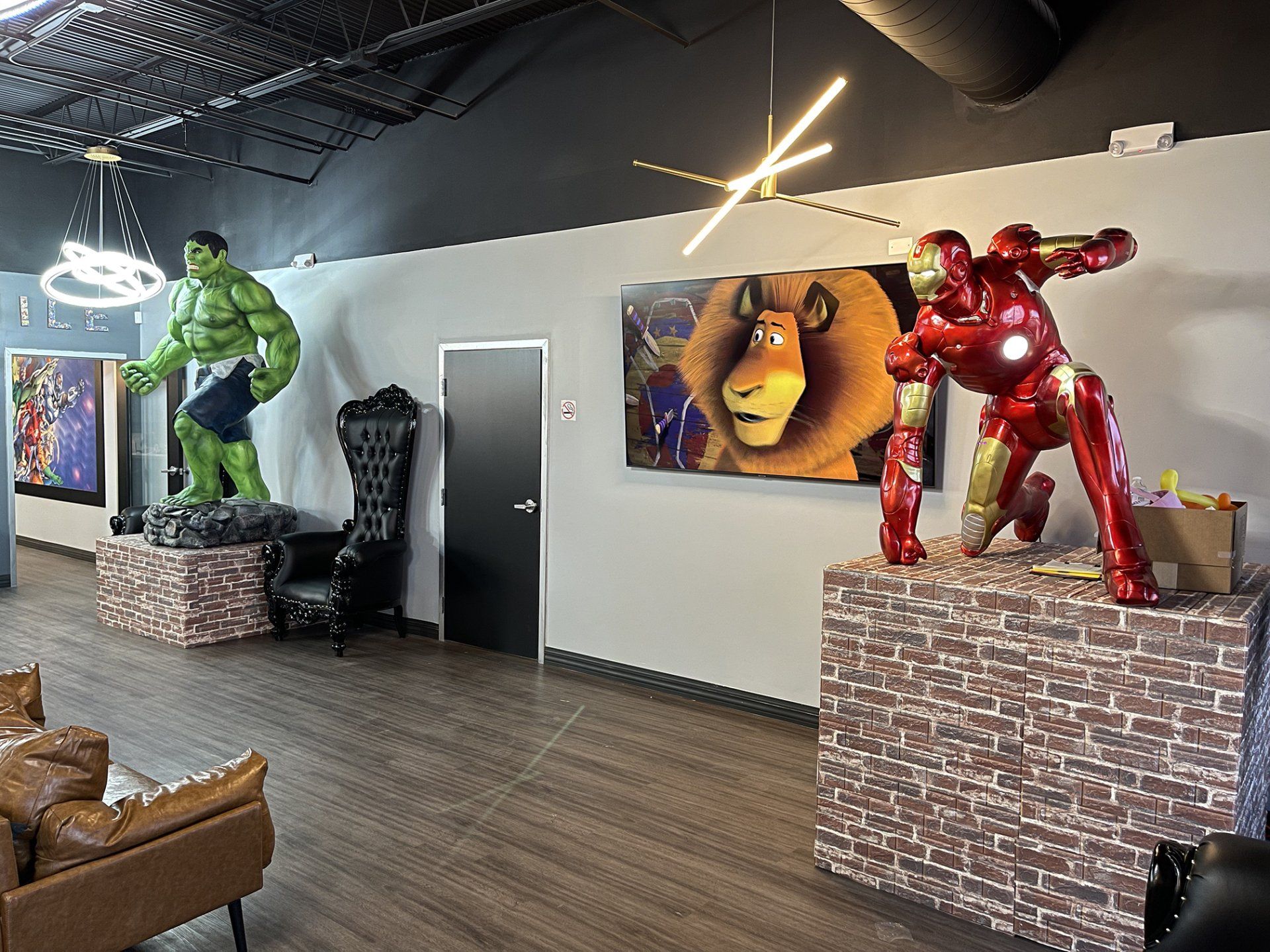 Lobby with large Iron Man and Hulk statues on brick pedestals beside a hallway.