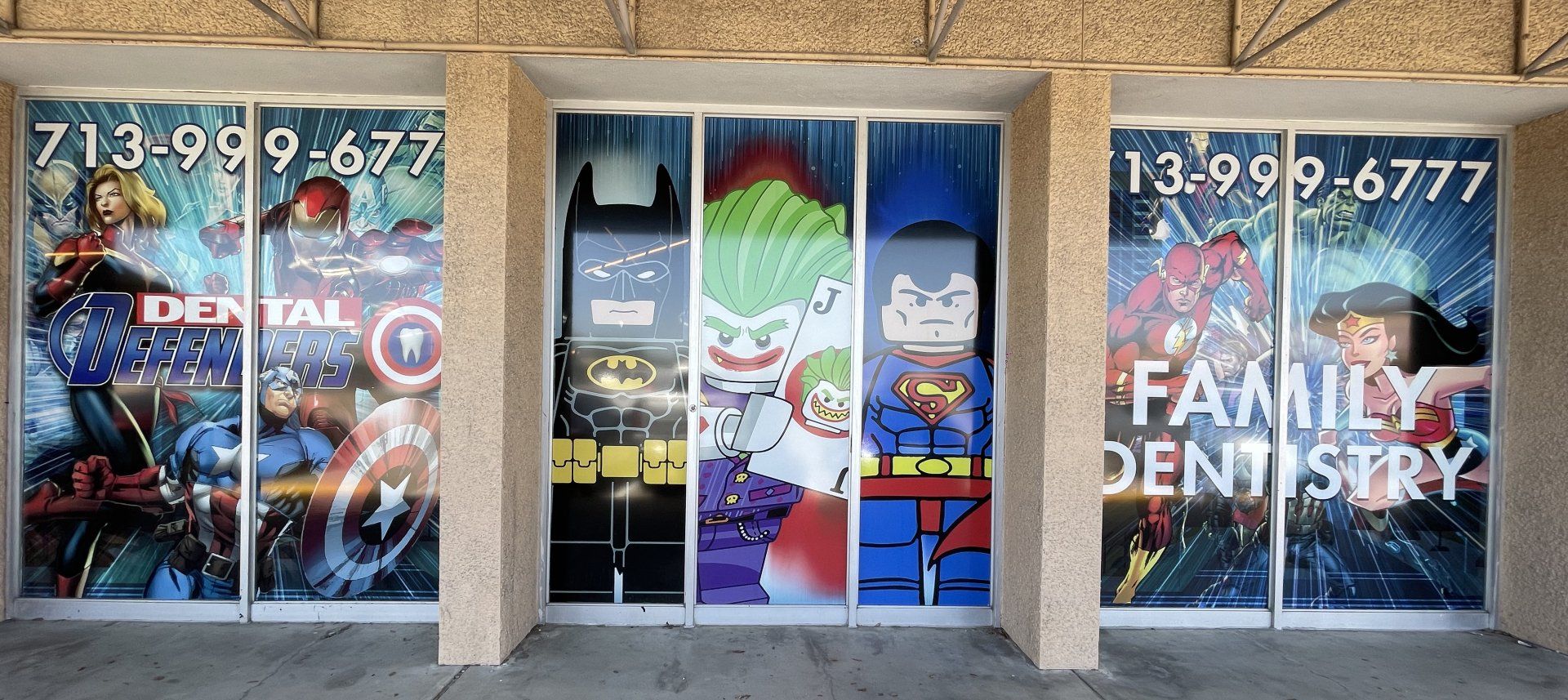 Storefront windows with colorful dental office signage and a blue center door; phone number displayed above.