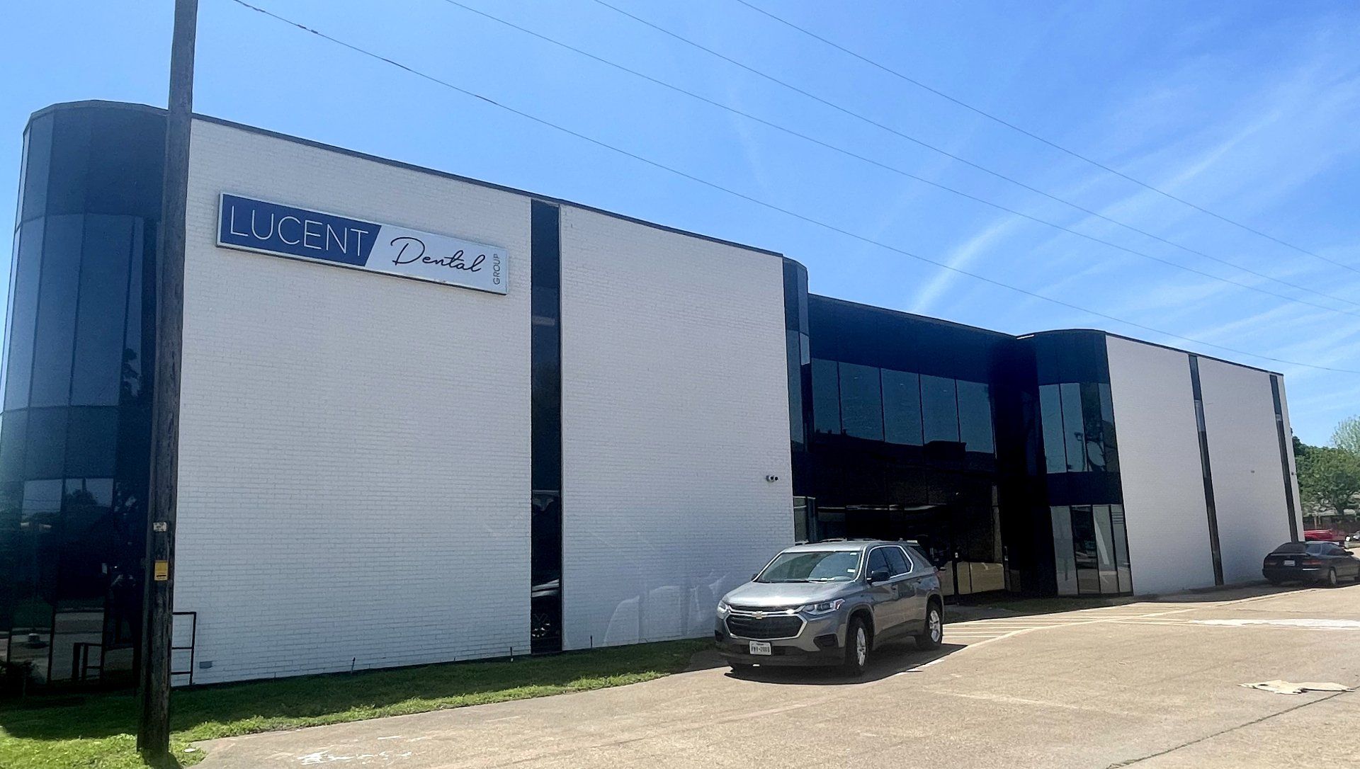 Modern commercial building with a parked SUV under a clear blue sky