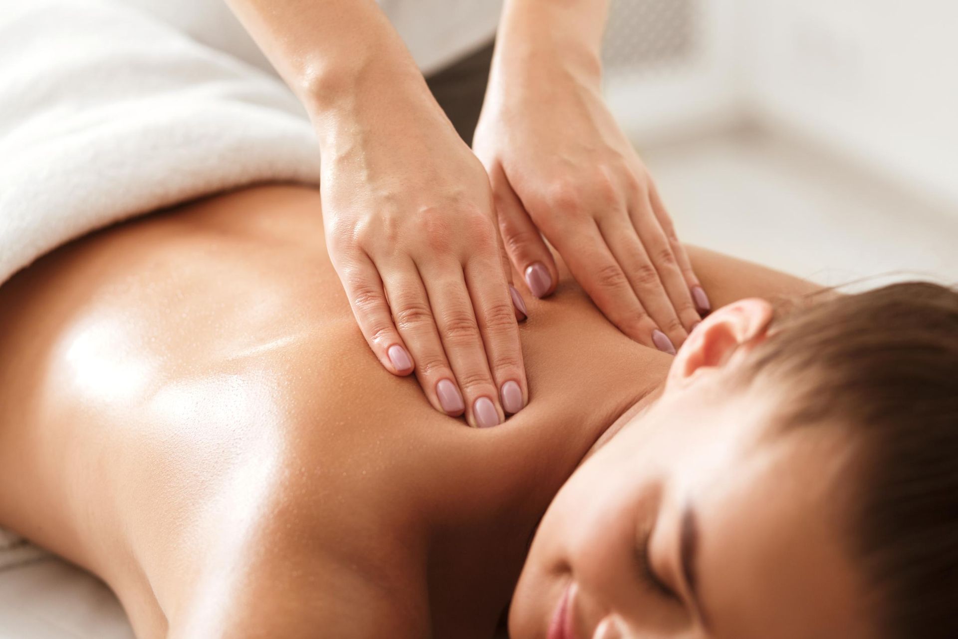 Hands giving a back massage to a reclining person on a white towel