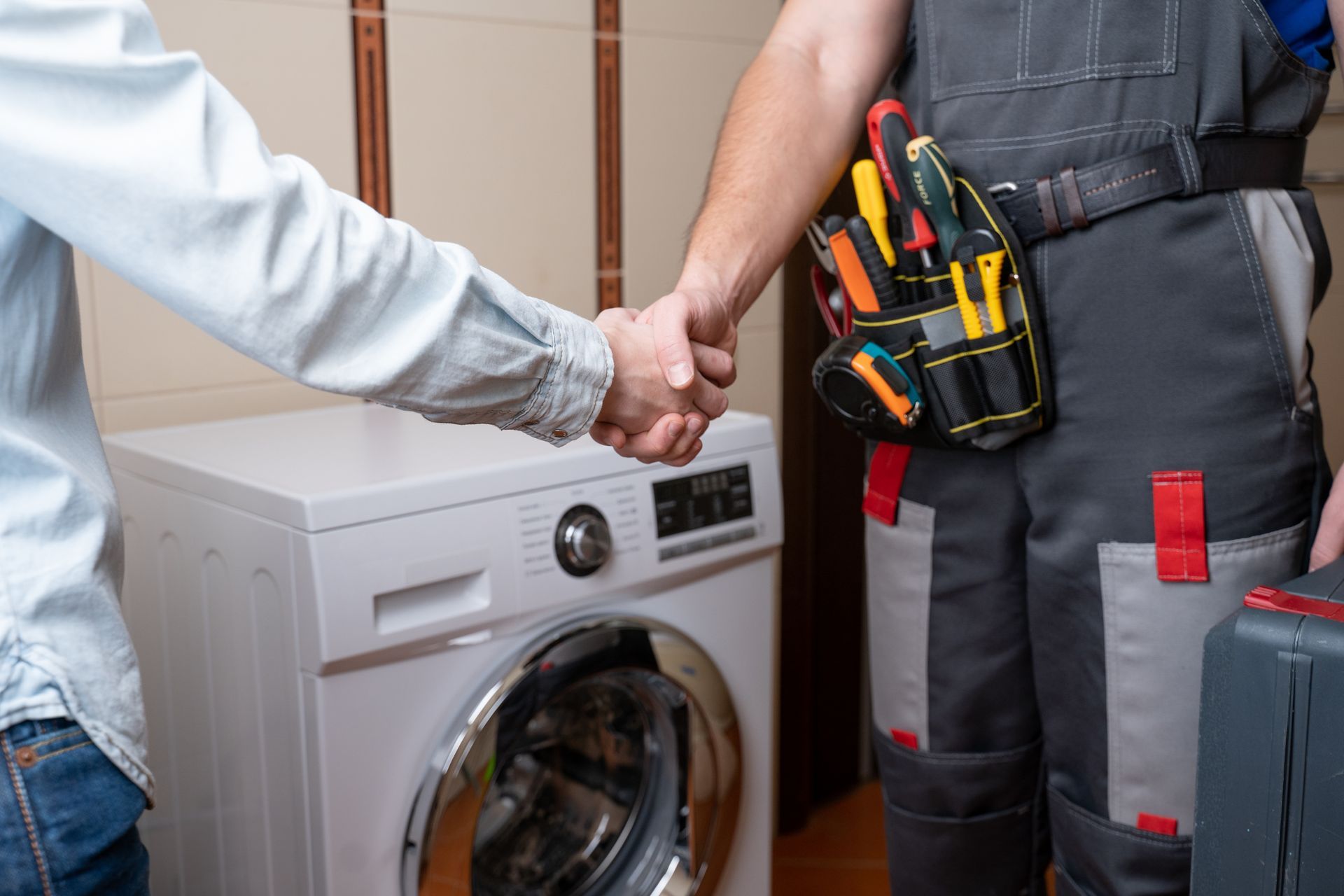a man is shaking hands with a plumber in front of a washing machine .