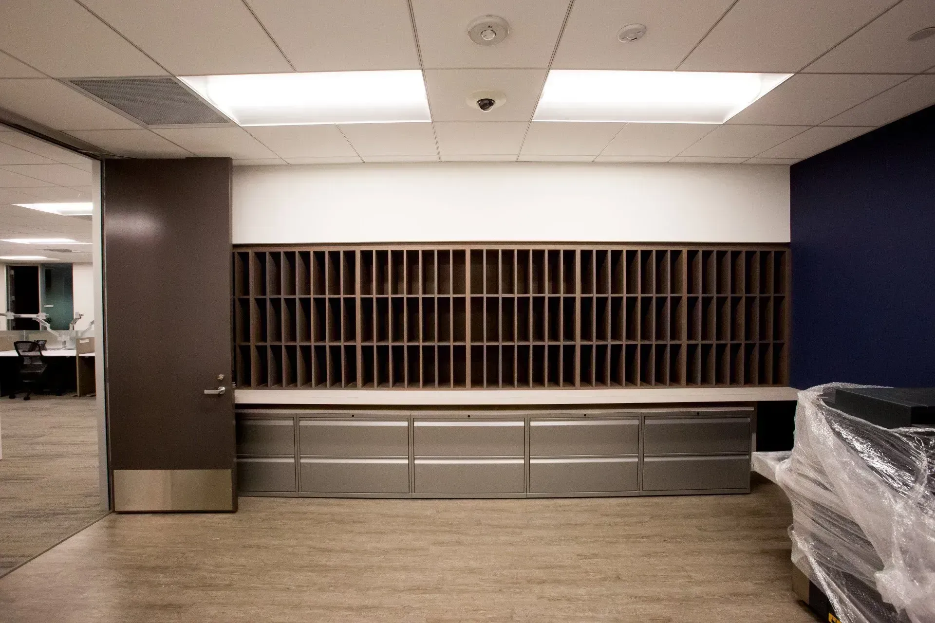 Empty office reception area with built-in cubby shelves, gray cabinets, and ceiling lights