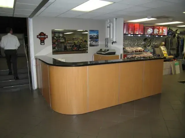 Indoor lobby with a curved wood reception counter and a person walking in the background.