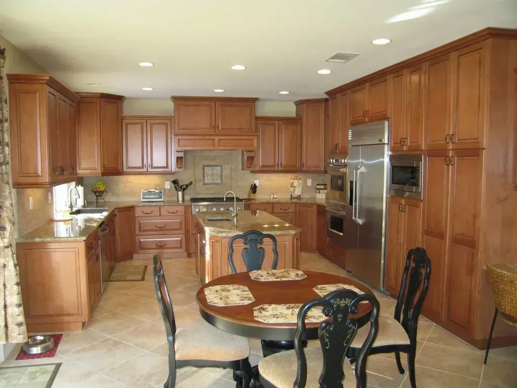 Wooden kitchen with stainless steel appliances, central island, and round dining table with chairs