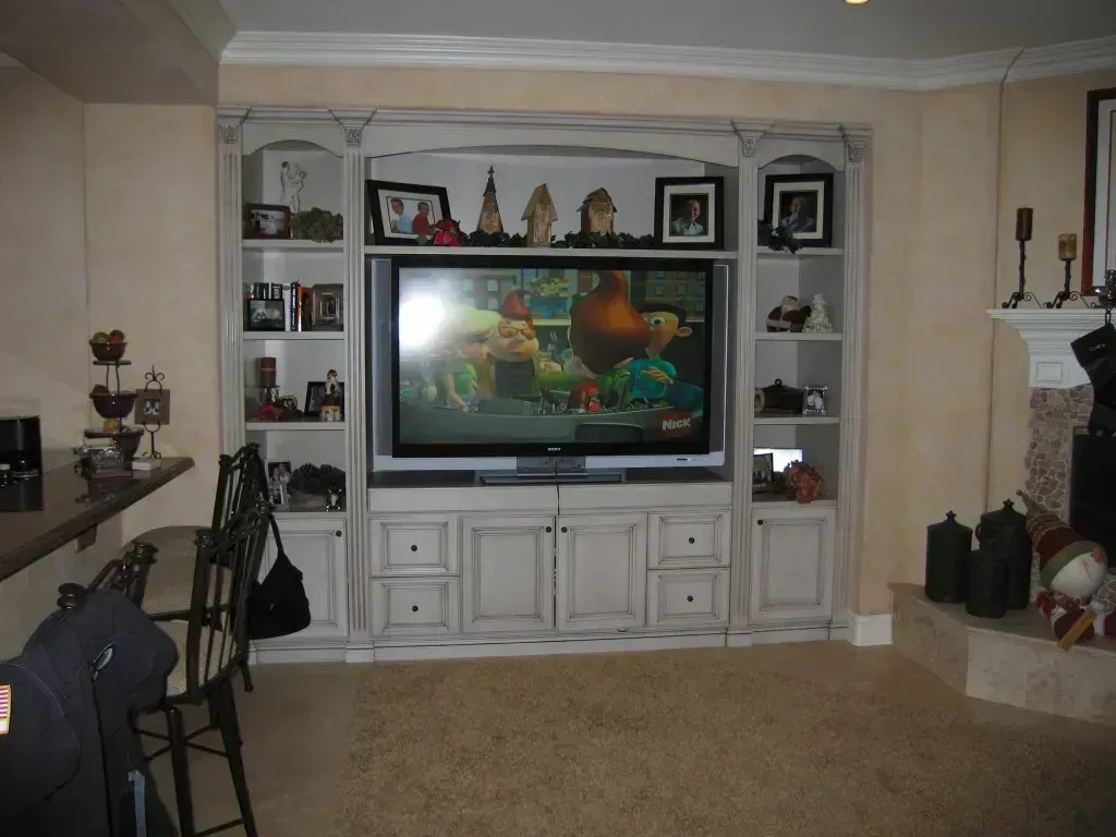 Living room with a large TV in a white entertainment center and fireplace on the right.