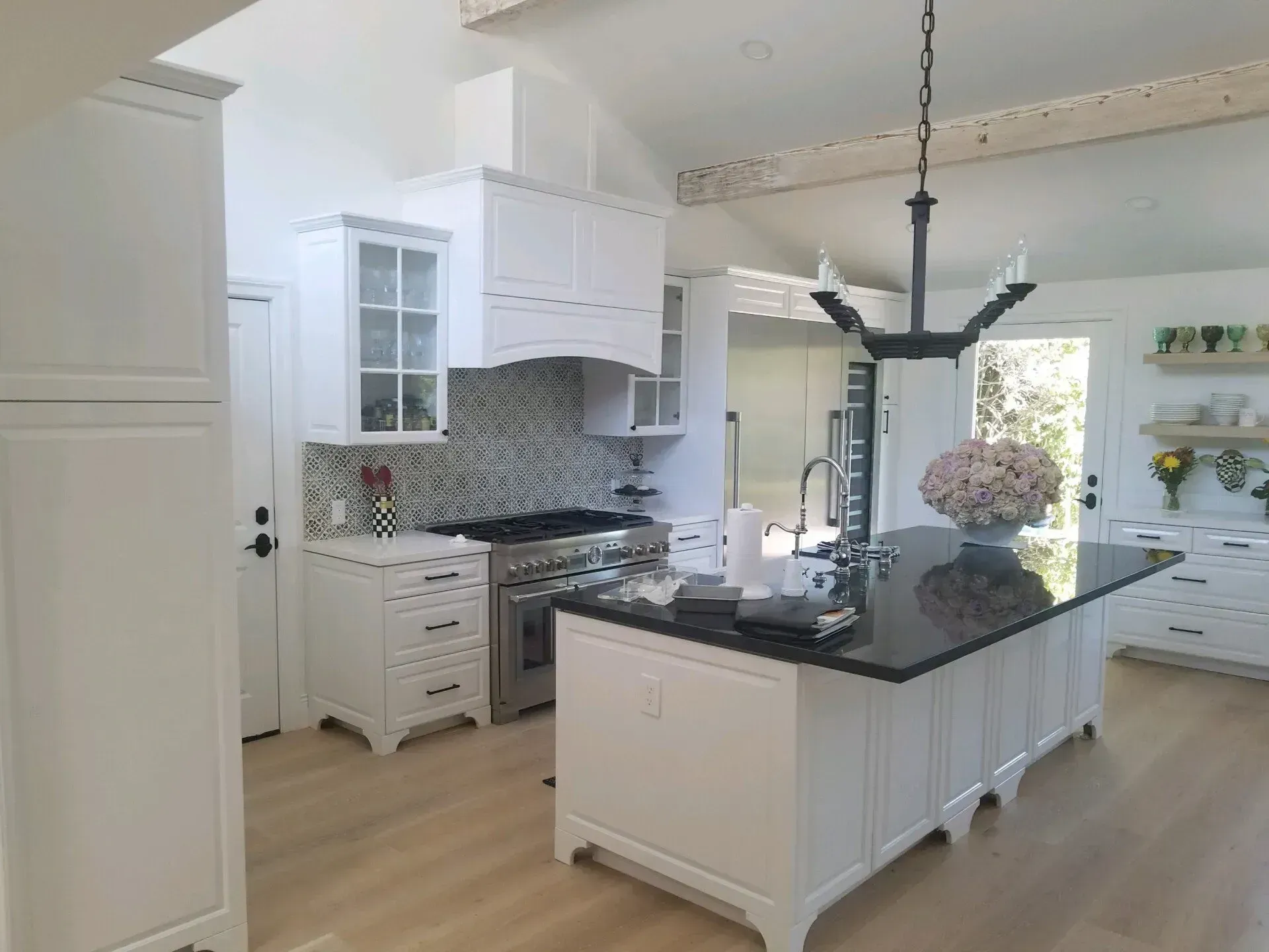 Bright white kitchen with island, dark countertops, mosaic backsplash, and pendant lights