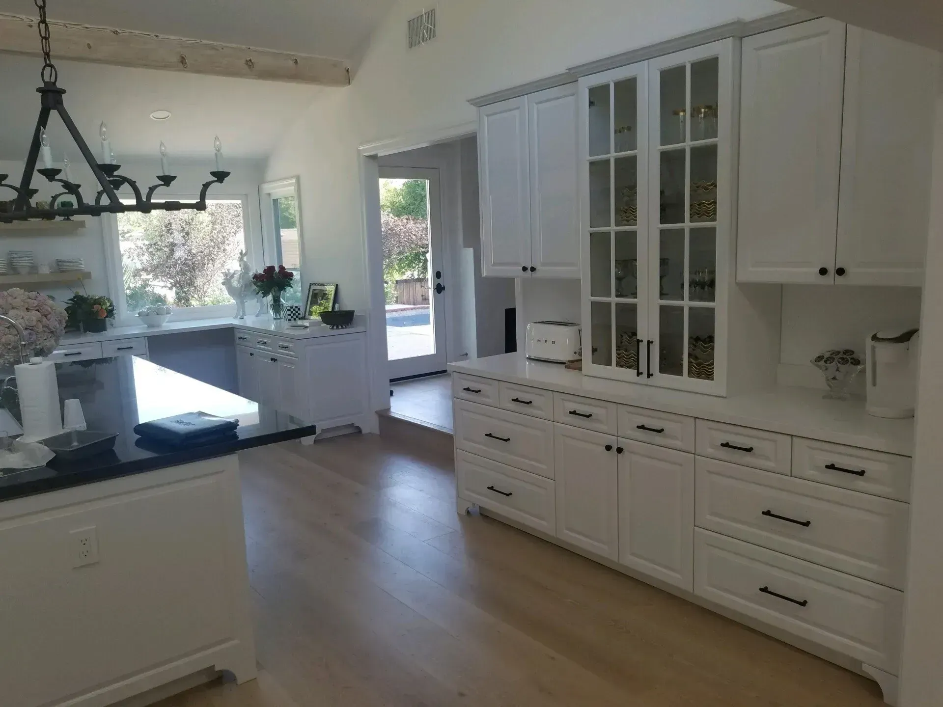 Bright white kitchen with island, cabinets, and large window overlooking a sunny view