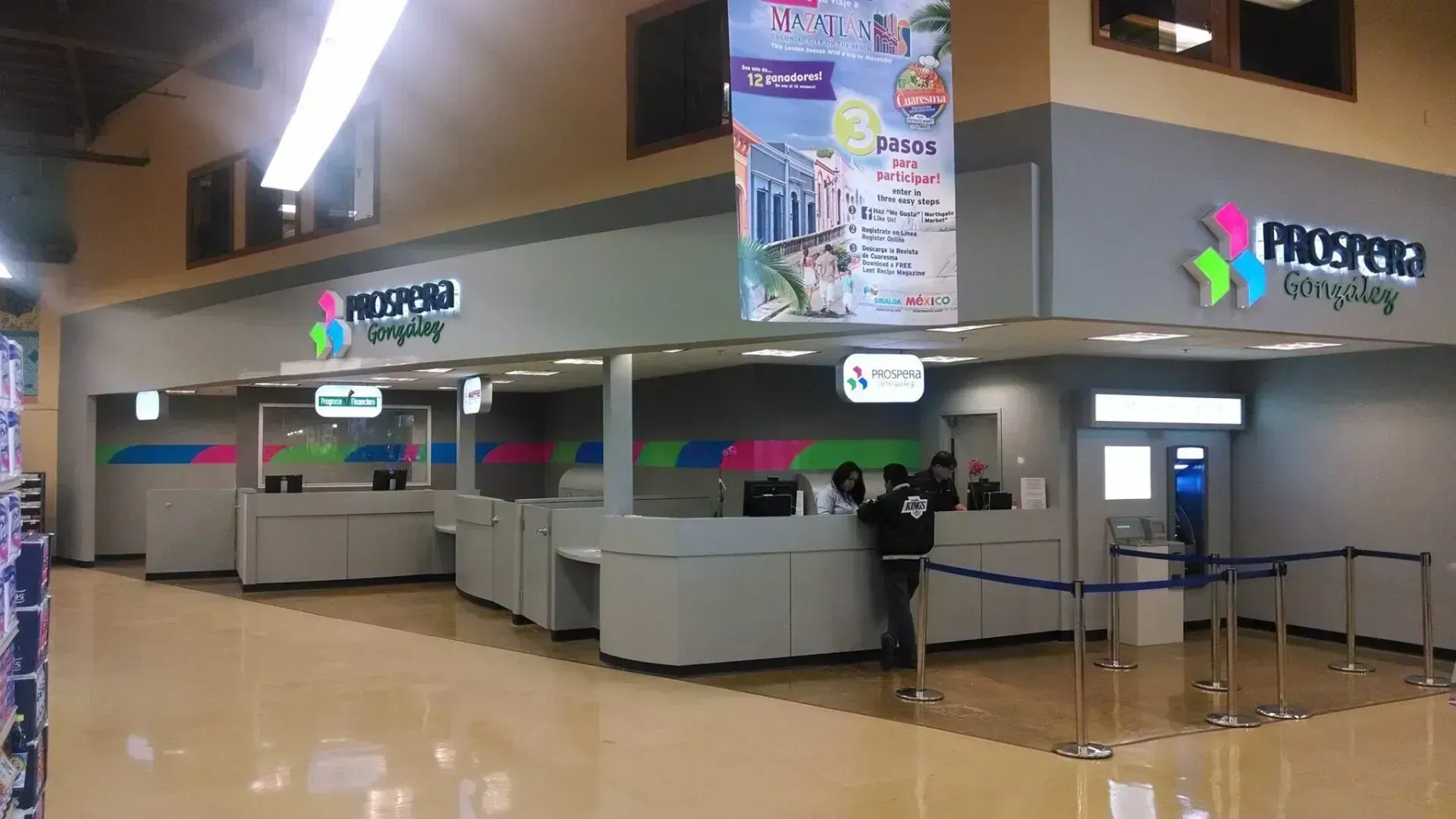 Airport check-in counters with stanchions and overhead signs in a brightly lit terminal.