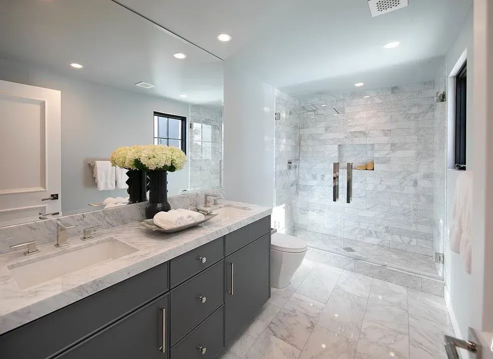 Modern bathroom with marble shower, gray vanity, and large mirror
