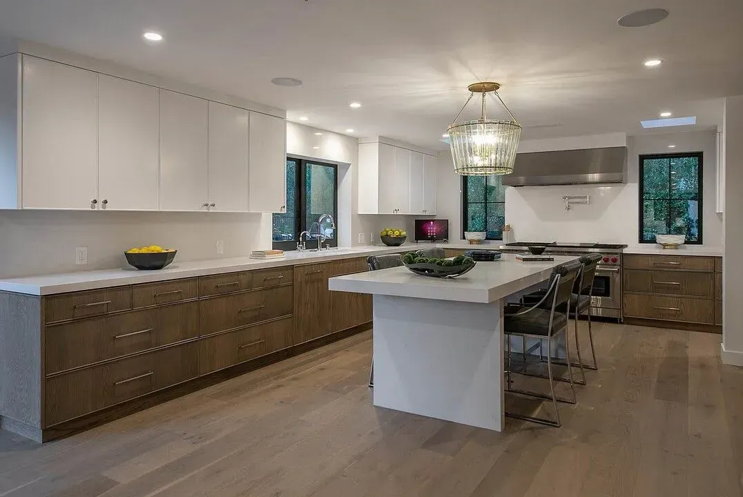 Modern kitchen with white island, wood cabinets, and pendant lights