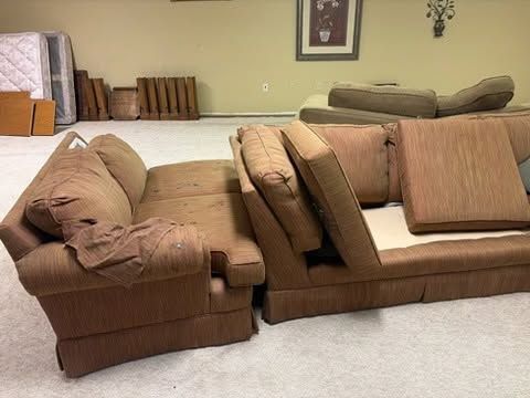 Brown sectional sofa with cushions in a living room with beige carpet and pale walls.