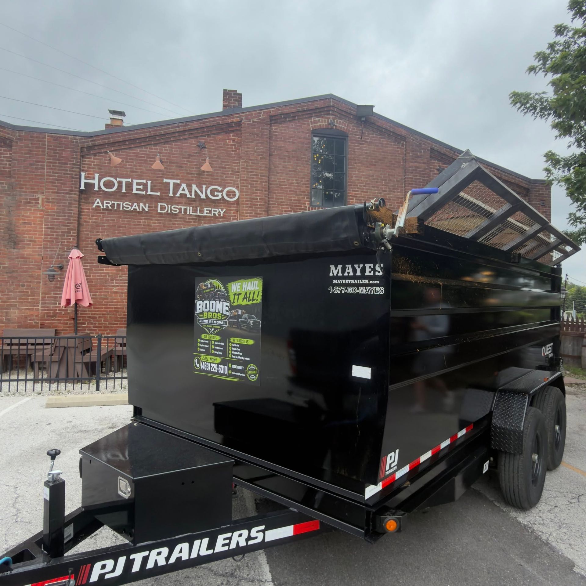 Black Mayes landscaping trailer parked outside Hotel Tango distillery brick building