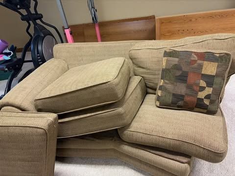 Beige sectional sofa with loose cushions and a patterned throw pillow in a living room.